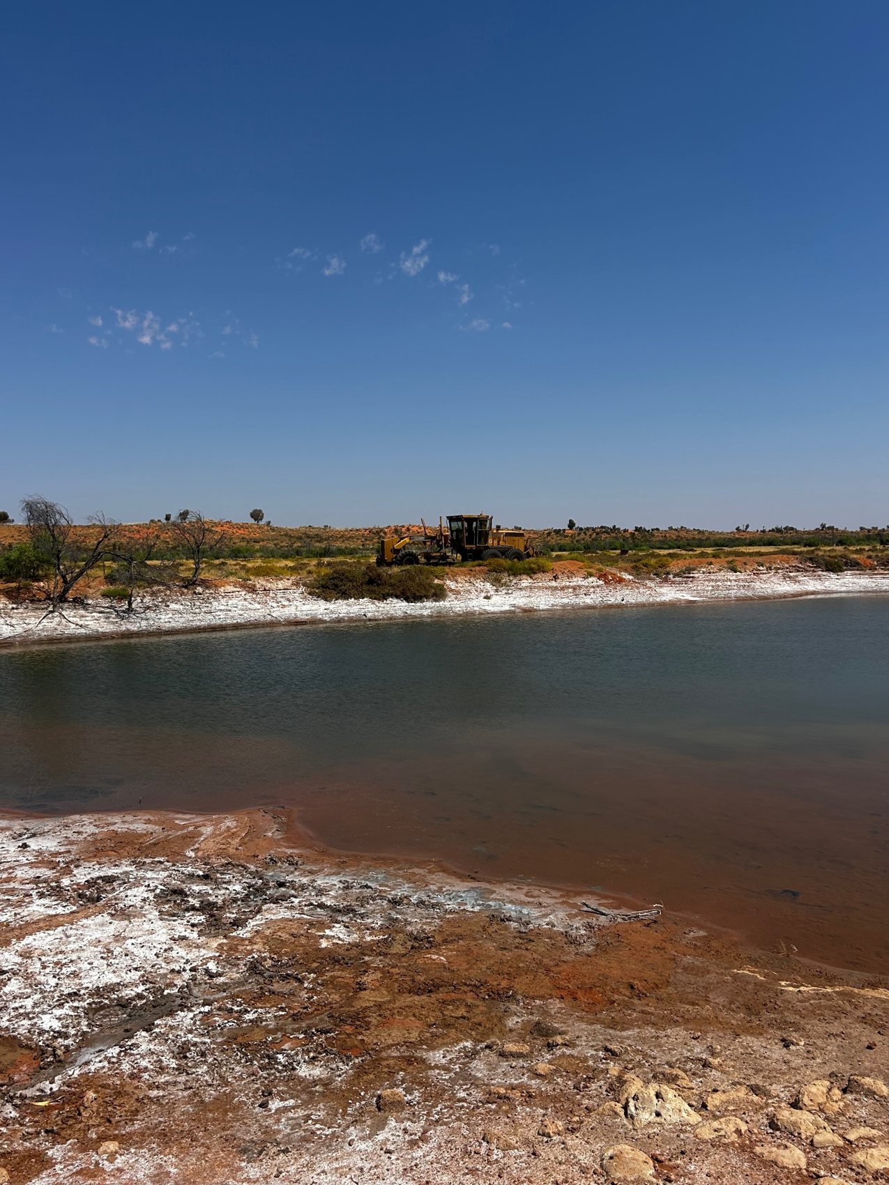 Motor grader beside a remote waterway